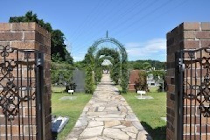 墓苑のエントランス。みずみずしいグリーンに縁どられた石畳の中央通路。フラワーアーチの奥には純白のガゼボ。